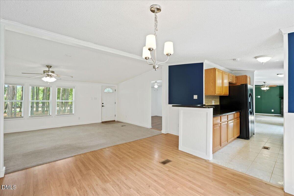 Open living and dining area beside a kitchen with wood cabinets and a navy accent wall.