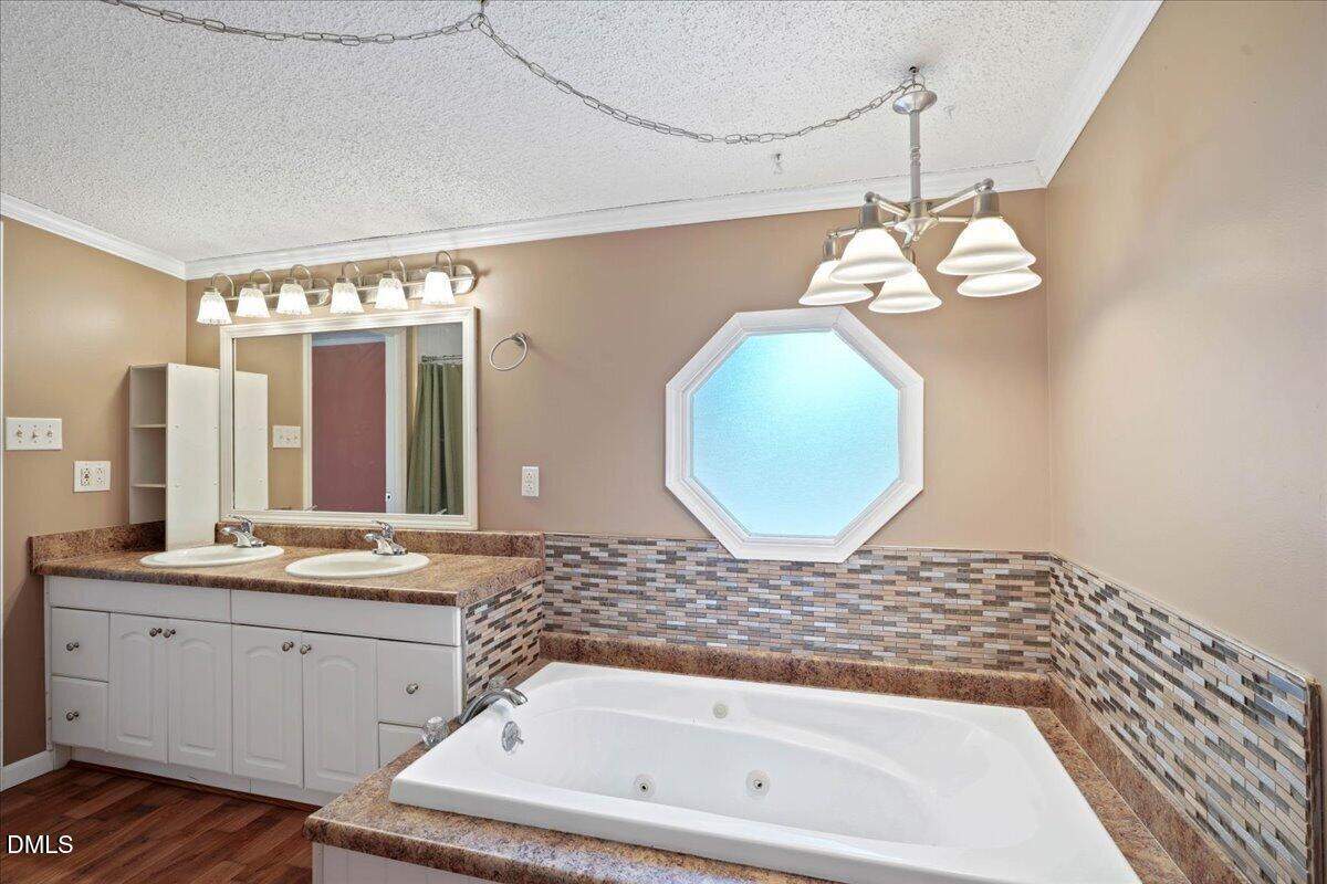 Bathroom with a large jetted tub, double vanity, and octagonal frosted window.
