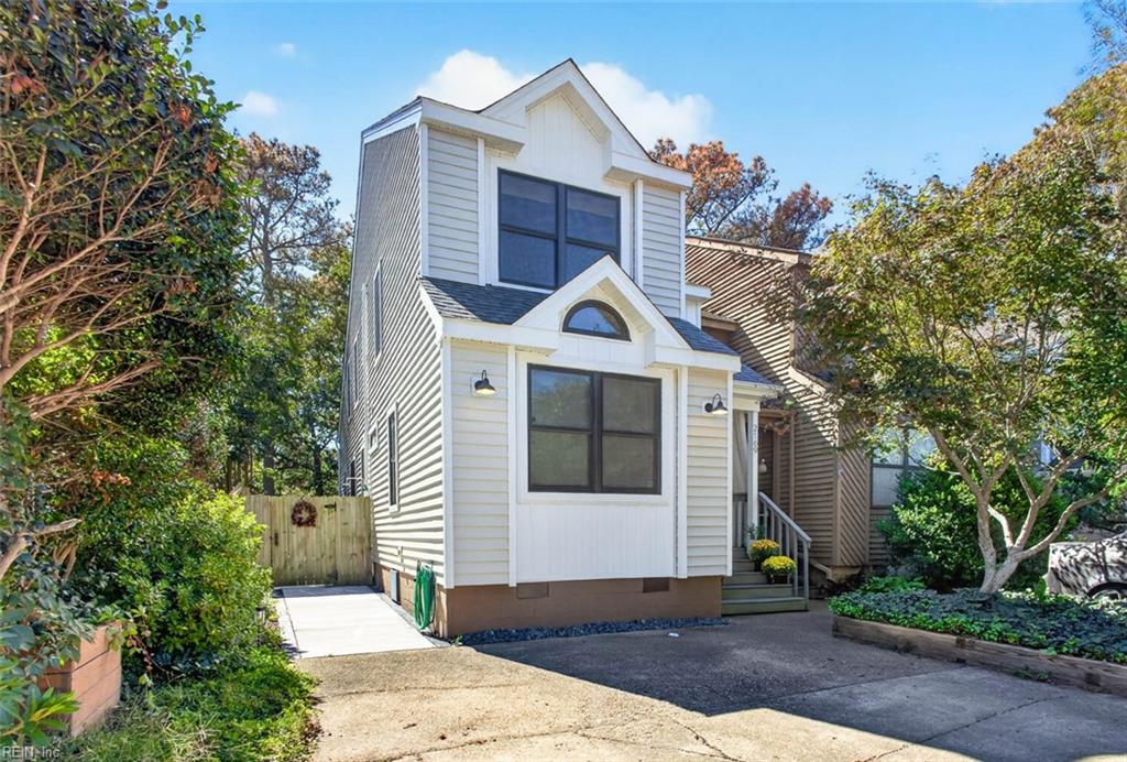 Two-story white-sided home with a small porch, driveway, and side walkway to a wooden gate.