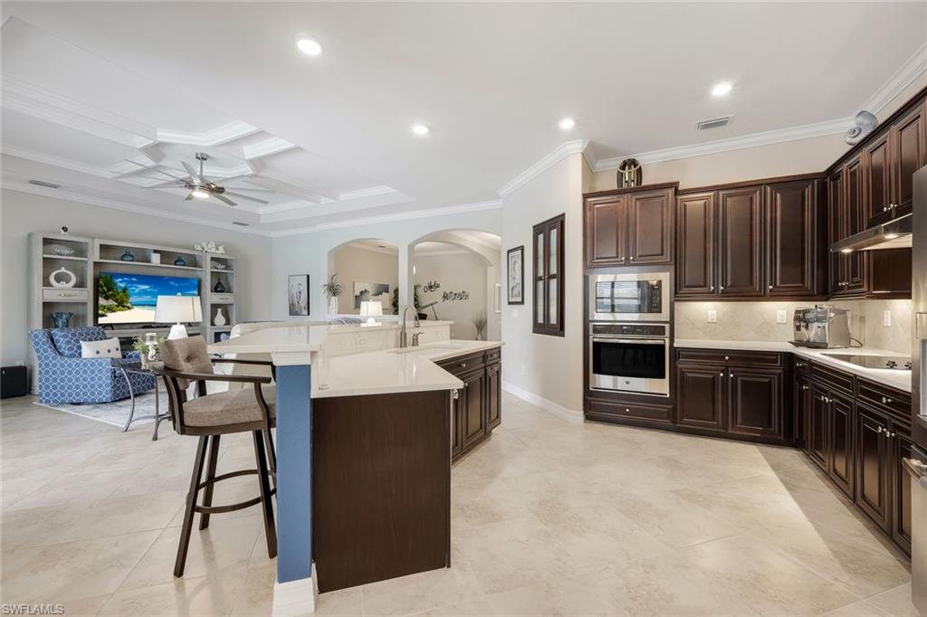 Spacious kitchen with dark wood cabinetry, a large island, and built-in stainless steel ovens.