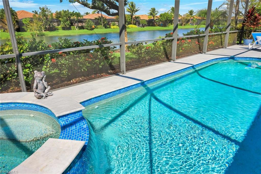 Screened pool and attached spa overlooking a canal, with tropical landscaping and homes across the water.