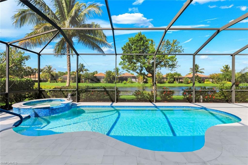 Screened pool and raised spa overlooking a lake, with palm trees beyond.