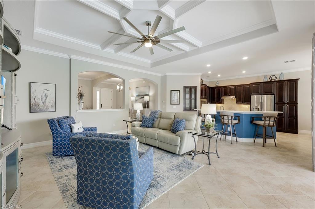 Open-plan living room with blue patterned chairs, coffered ceiling, and blue kitchen island.