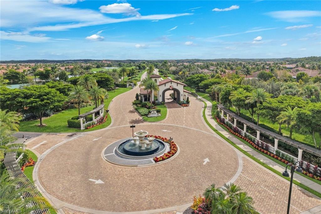 Landscaped community entrance with a central fountain and arched gatehouse, viewed from above.