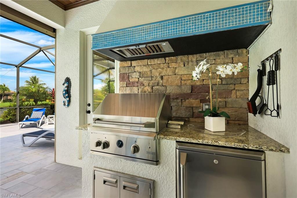 Covered outdoor kitchen with a stainless-steel built-in grill, stone backsplash, and granite counter.