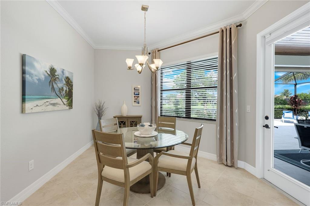 Dining room with a round glass table, chandelier, and glass door to the screened patio.