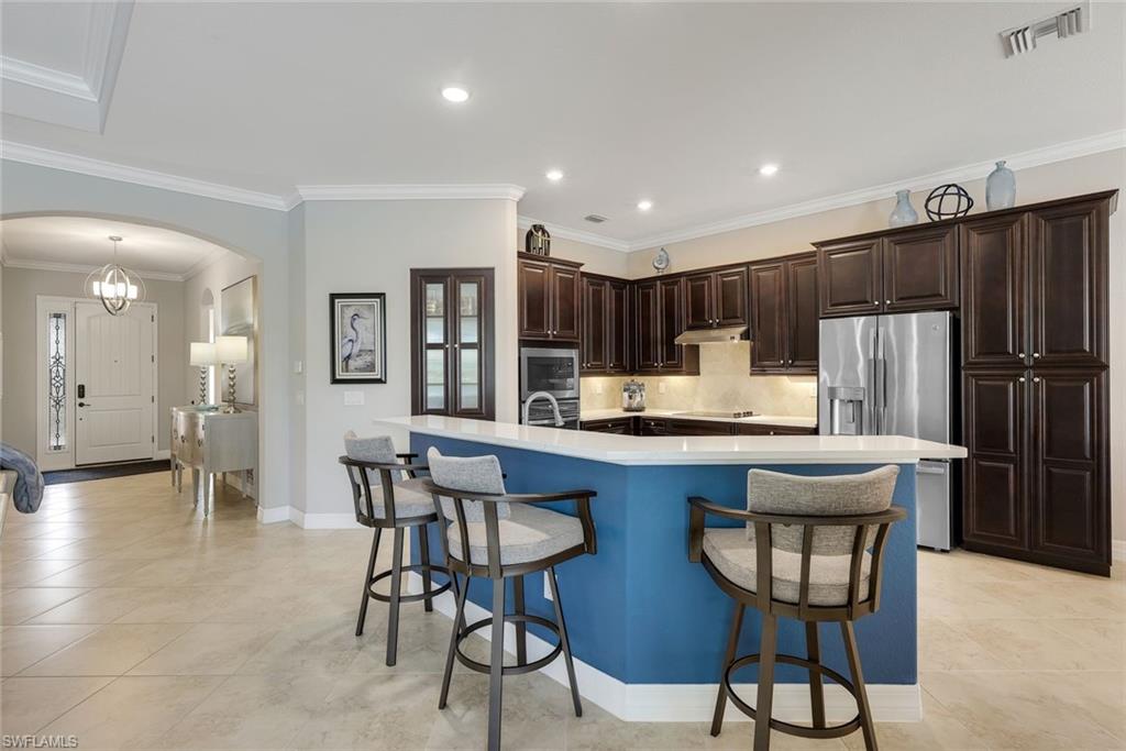 Kitchen with dark wood cabinets and a large blue island with bar seating.