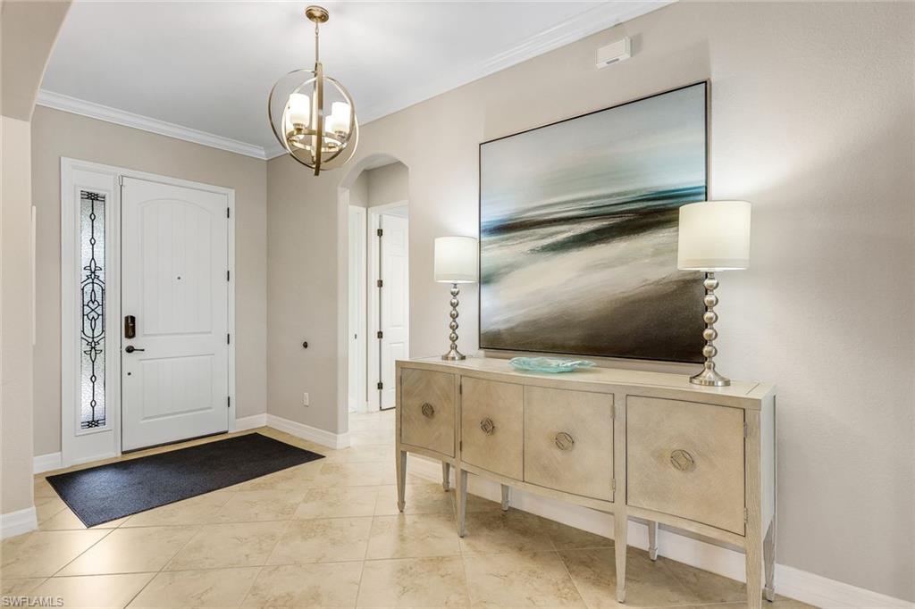 Entry foyer with a white front door, decorative glass sidelight, globe chandelier, and console beneath abstract artwork.
