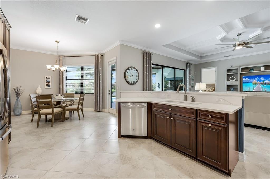 Kitchen and dining area with dark wood cabinetry, a white island, and a dining table by the window.