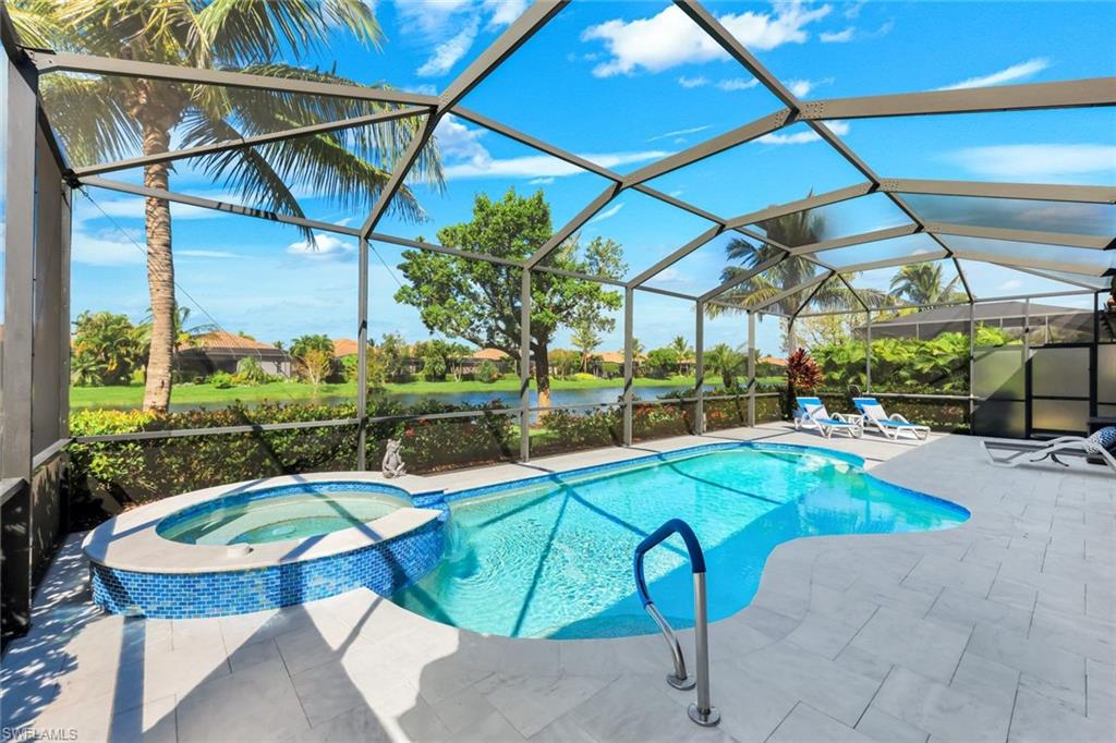 Screened pool and round spa beside a tiled patio, overlooking a pond.