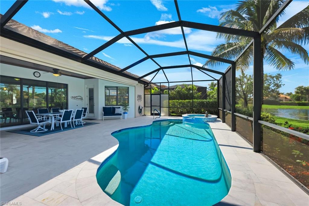 Screened pool lanai with curved swimming pool, spa, outdoor dining area, and lake view.