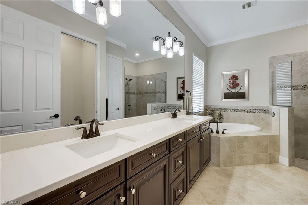 Bathroom with a long double vanity, built-in soaking tub, and glass-enclosed shower.