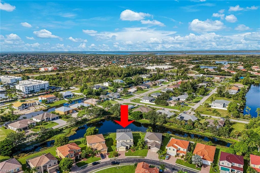 Aerial view of a Cape Coral home beside a canal, marked by a red arrow.