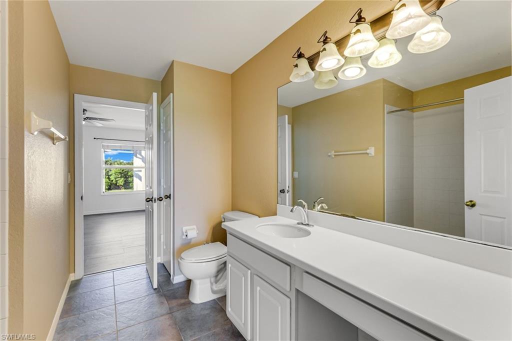 Bathroom with a long white vanity, large mirror, gray tile floor, and tiled shower.