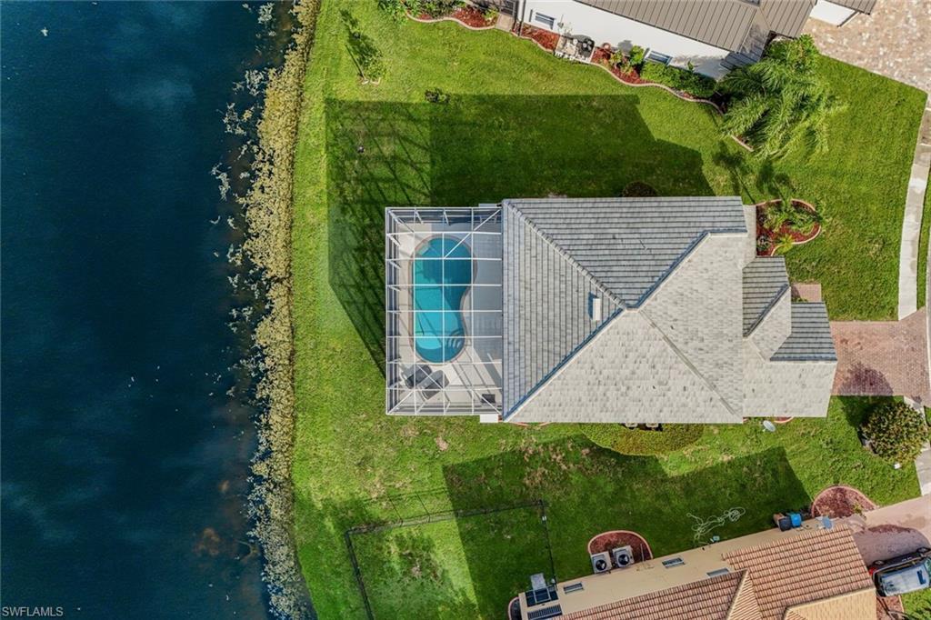 Waterfront home with a screened pool beside a canal, viewed from above.