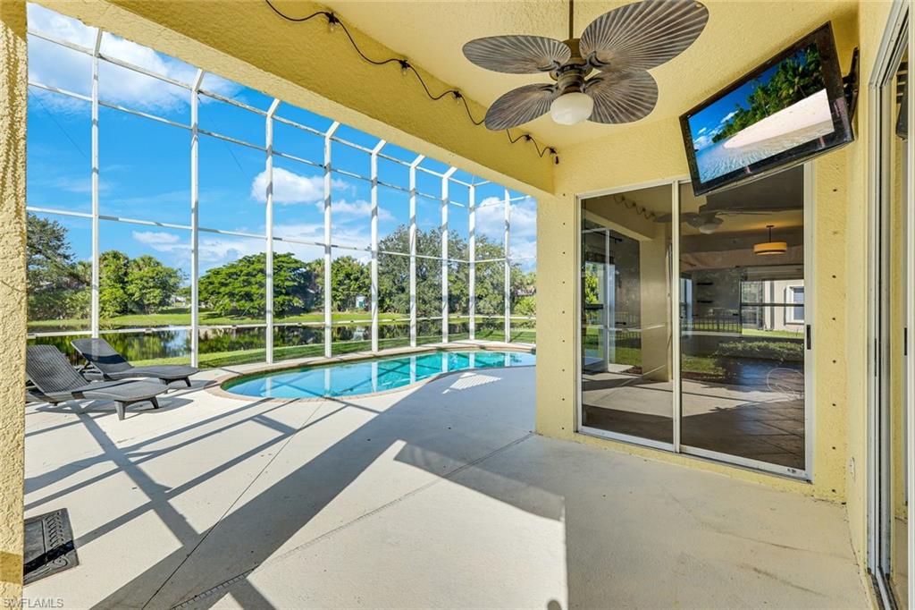 Screened lanai with a curved pool, lounge chairs, and a waterway view.