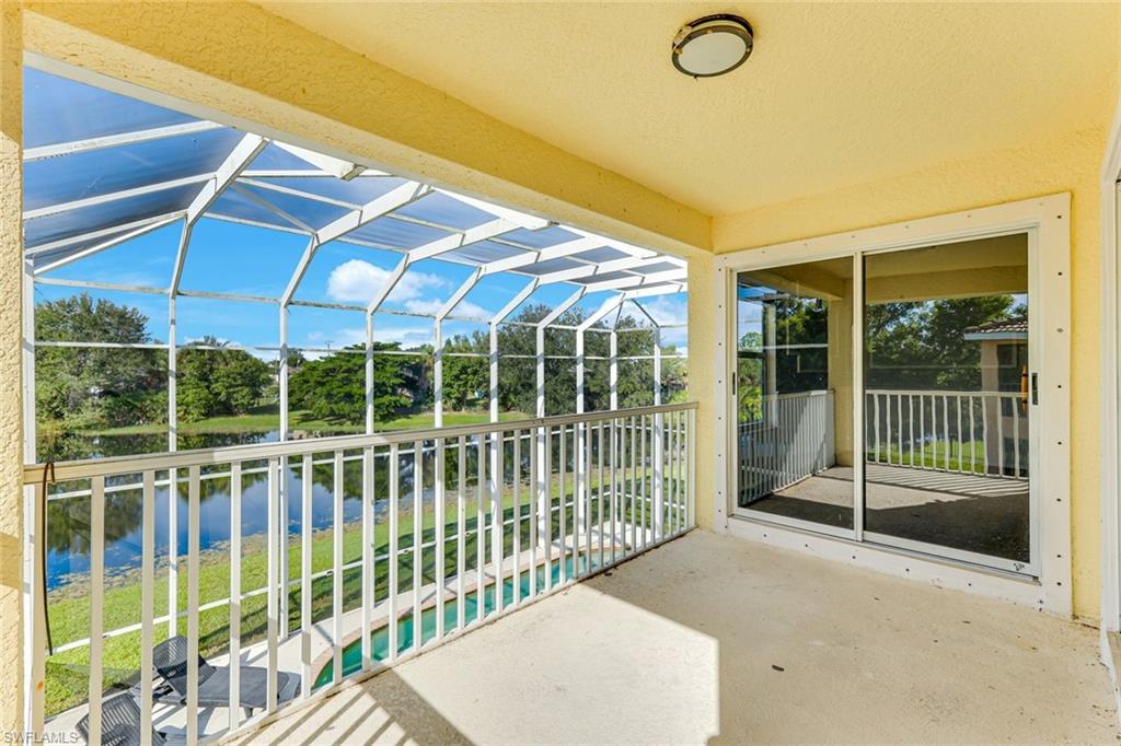 Screened lanai overlooking a canal, with a white railing and a glimpse of the pool.