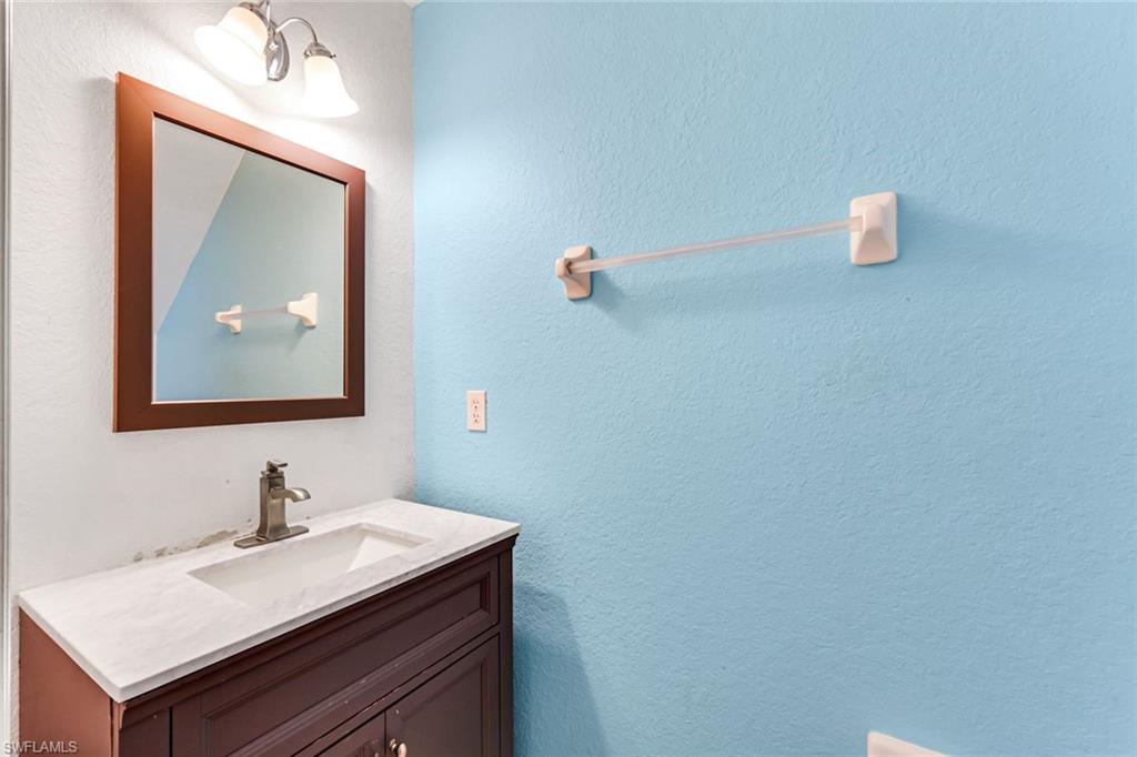 Bathroom vanity with a framed mirror and towel bar against a bright blue wall.