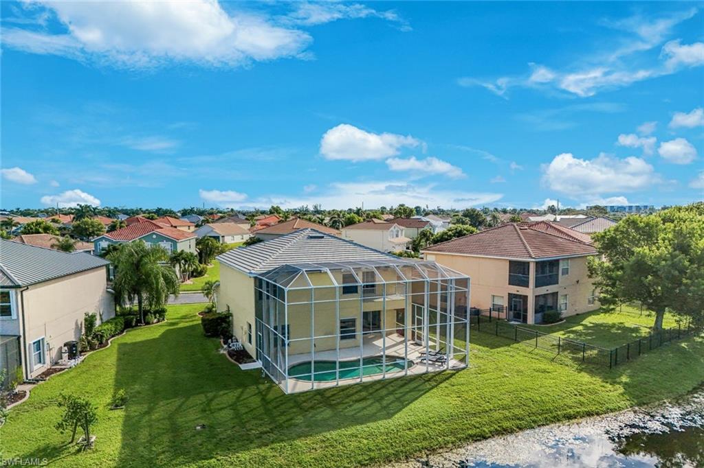 Aerial view of a waterfront home with a screened pool enclosure beside a canal.