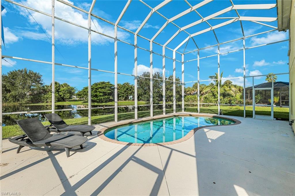 Screened pool deck with a curved swimming pool, lounge chairs, and water visible beyond the enclosure.