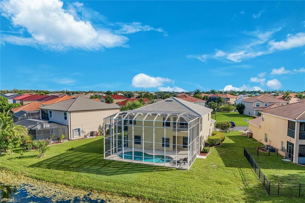 Aerial view of a two-story home with a screened pool and canal behind the yard.