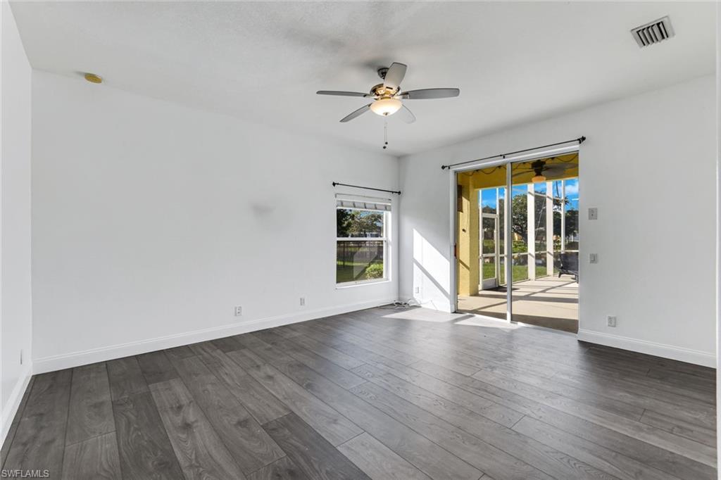 Empty room with gray plank flooring, ceiling fan, and sliding glass doors to a covered patio.