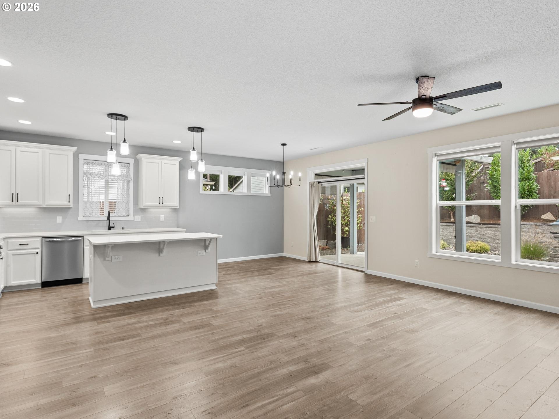 Open-plan kitchen and dining area with a large white island, wood-look floors, and sliding glass doors.