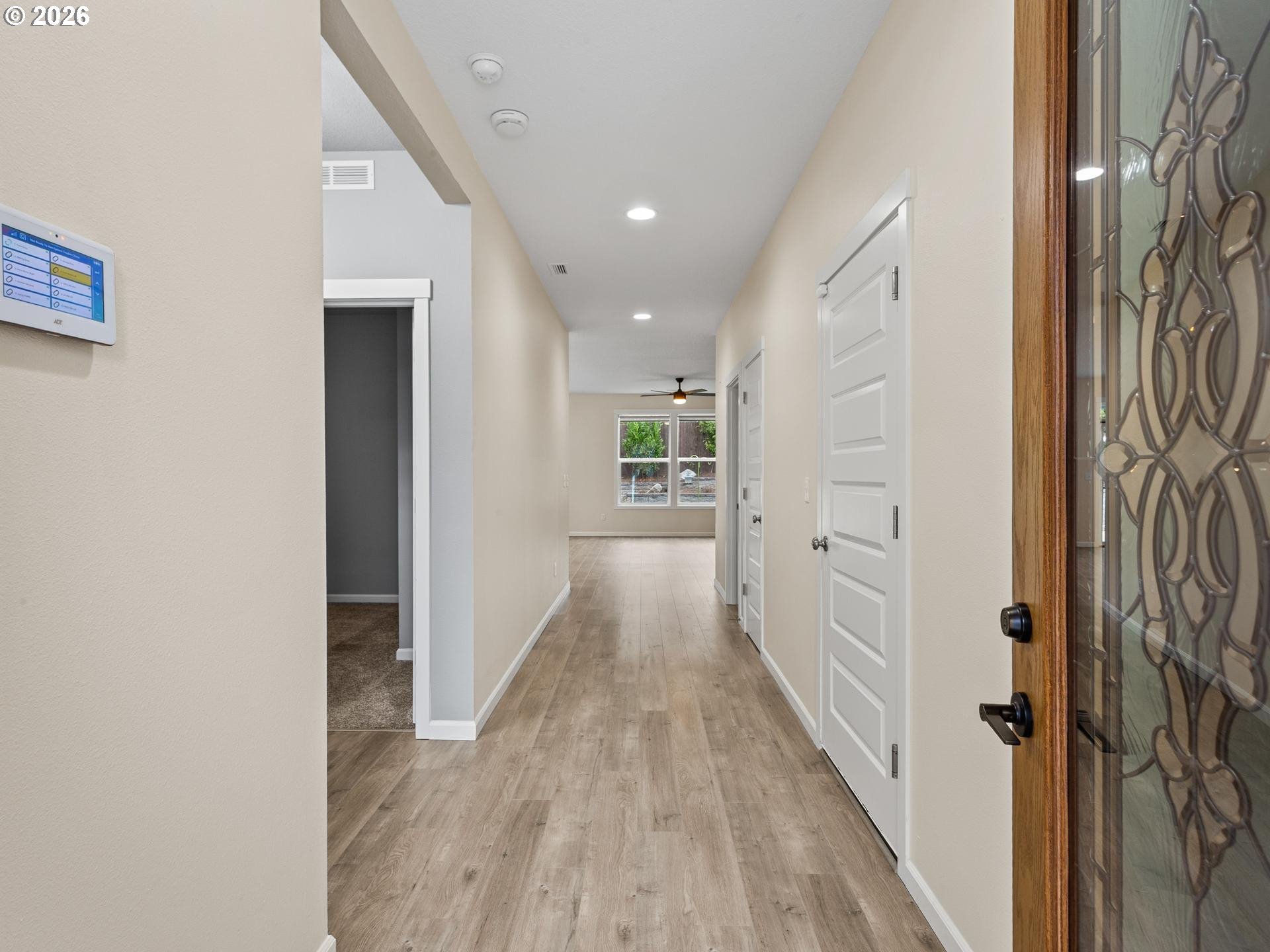 Entry hallway with wood-look flooring, white doors, and a decorative glass front door.