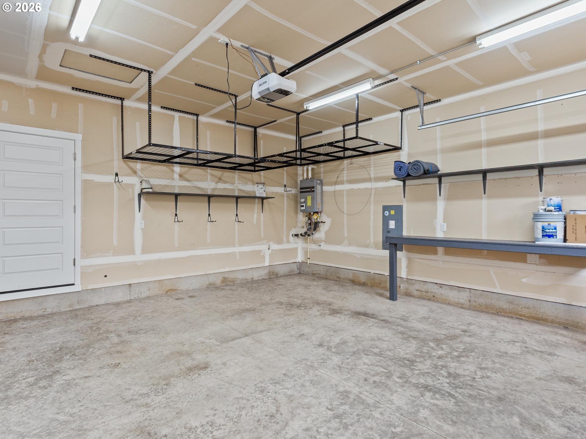 Garage with overhead storage racks, wall shelving, and a long workbench.