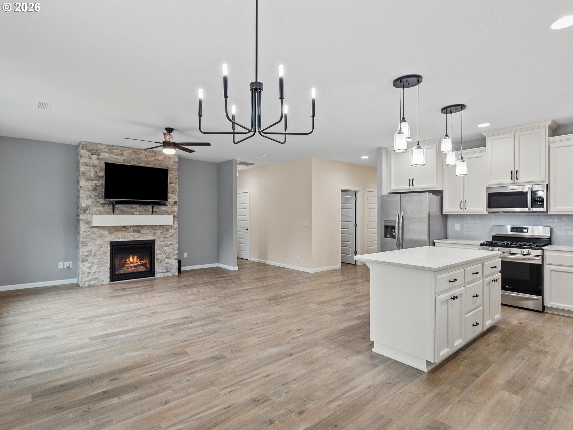 Open-plan kitchen and living area with a large white island and stone fireplace.