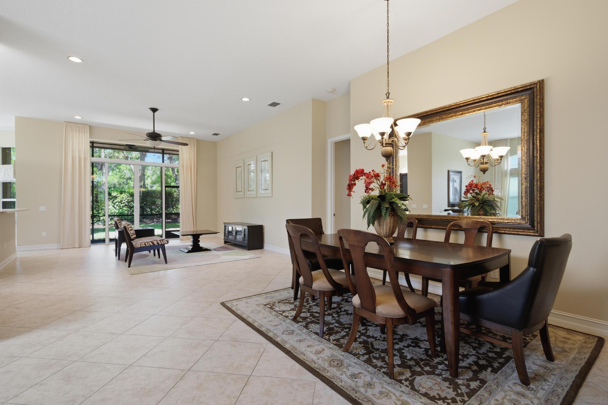 Open dining and living area with a dark wood table, ornate mirror, and garden visible through sliding glass doors.