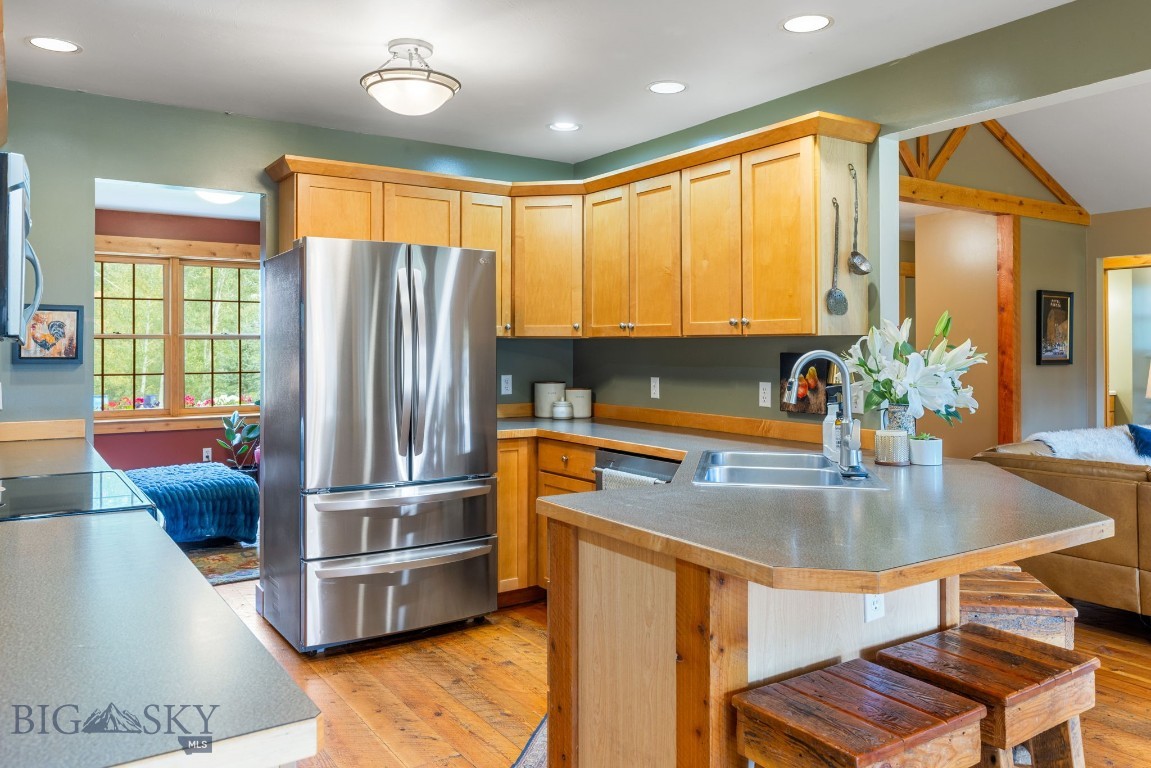 Kitchen with honey-colored cabinets, stainless steel refrigerator, and a large island with wooden stools.