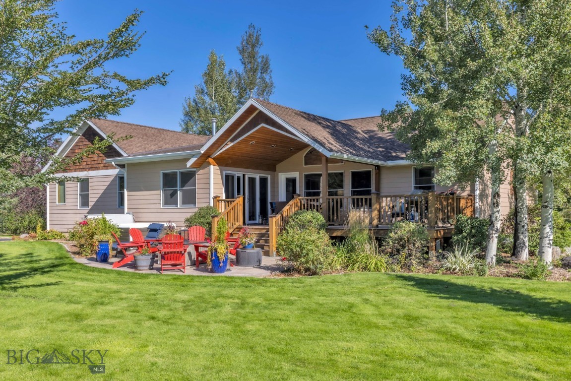 Home with a covered wooden deck, red Adirondack chairs, and a broad green lawn.