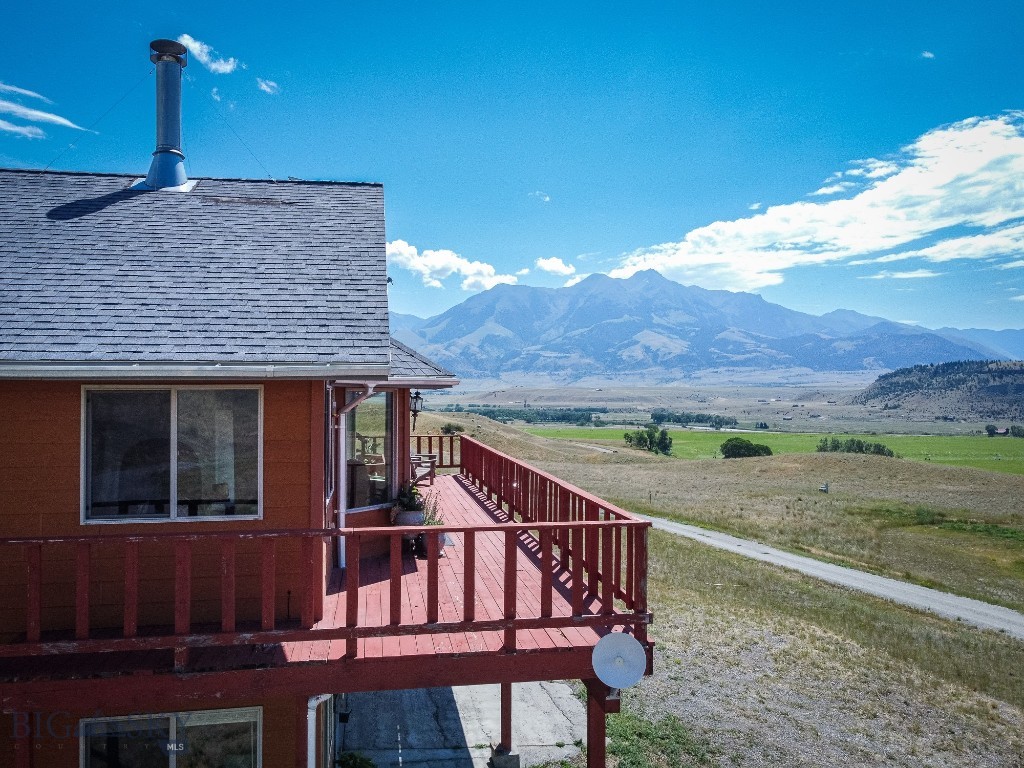 Home with a red-railed deck overlooking an open valley and mountain range.