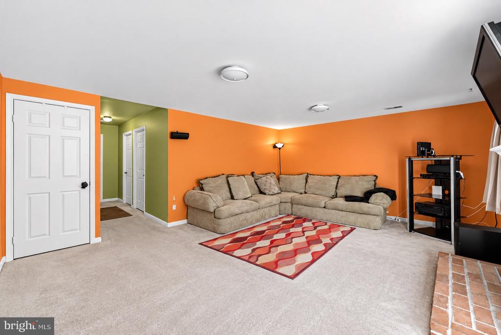 Living room with an orange accent wall, beige sectional, patterned rug, and carpet.