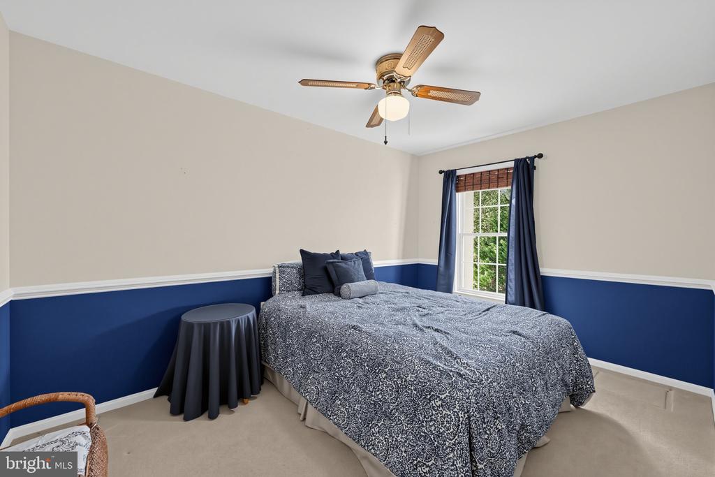 Bedroom with a patterned bedspread, navy lower walls, and a window framed by dark curtains.