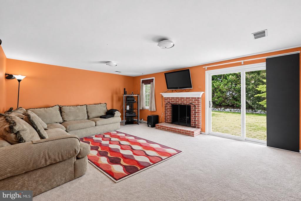 Living room with an orange accent wall, beige sectional, brick fireplace, and sliding doors to the yard.