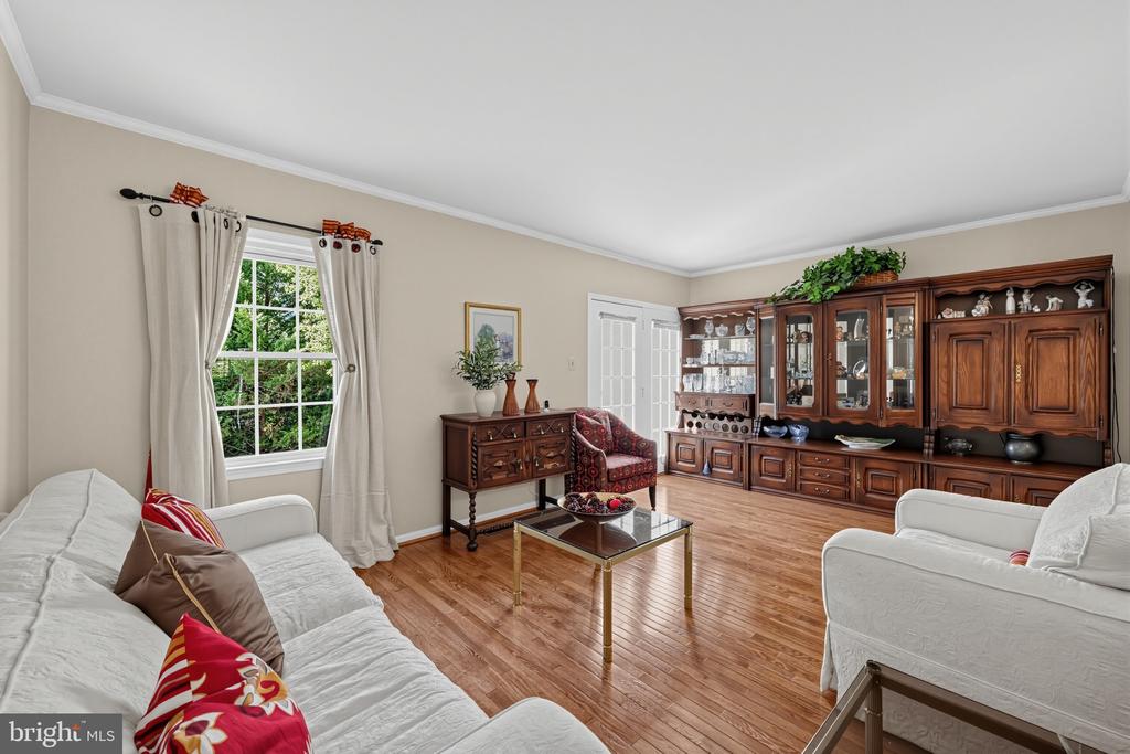 Living room with hardwood floors, white sofas, and a large dark wood display cabinet.