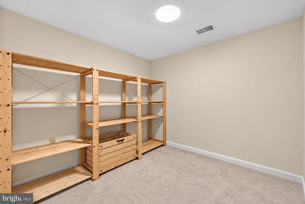 Storage room with extensive wooden shelving and a built-in drawer chest.