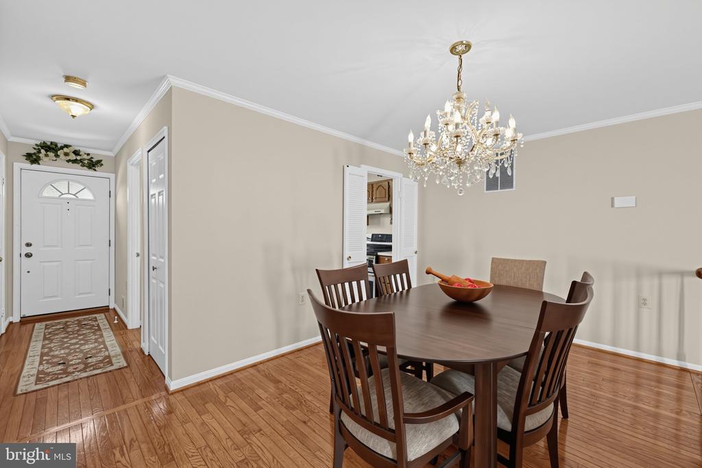 Dining room with a crystal chandelier, dark wood dining set, and hardwood floors beside the entry foyer.
