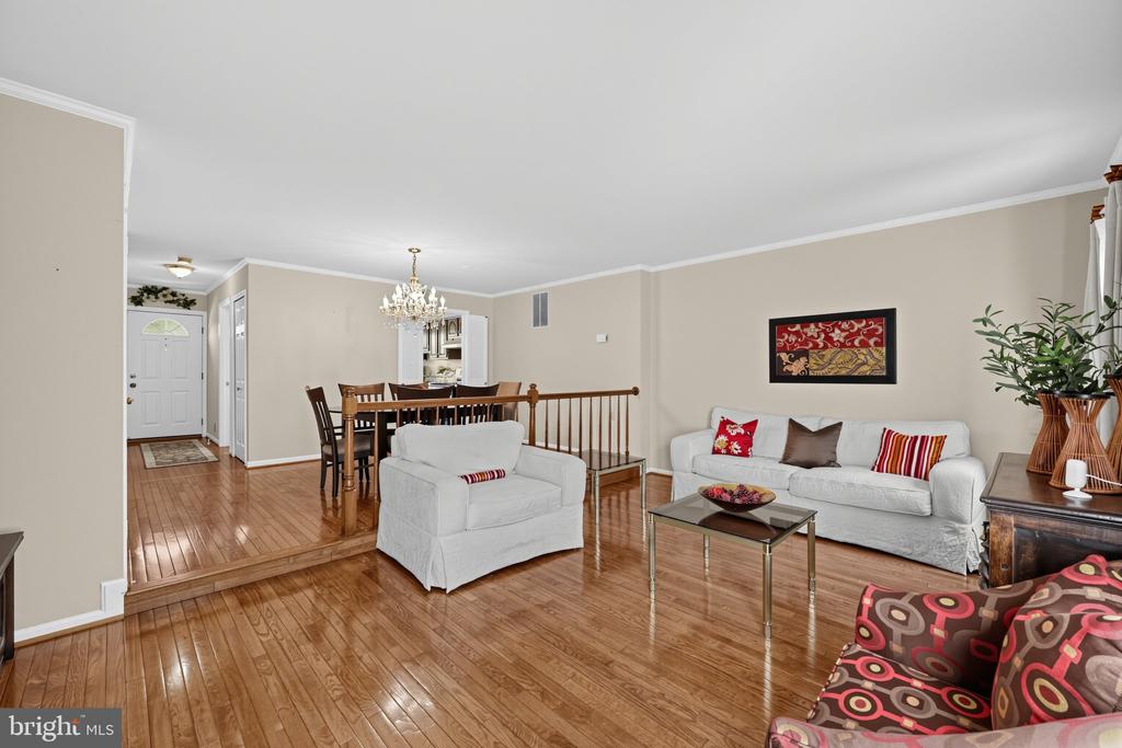 Living room with hardwood floors, white sofas, and an adjoining dining area.