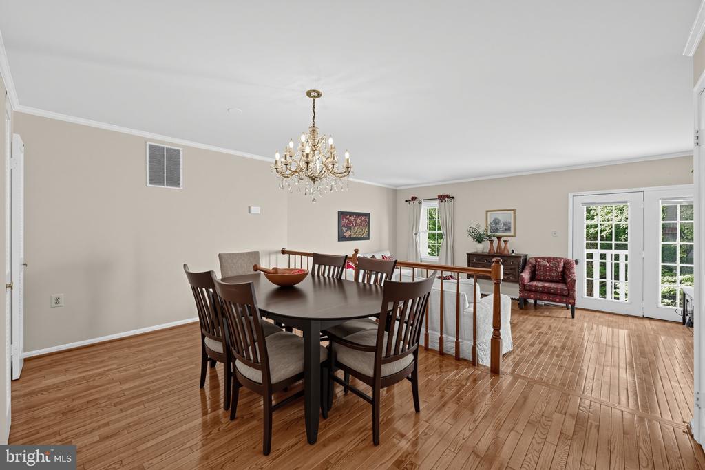 Dining room with a dark wood table, chandelier, hardwood floors, and glass patio doors.