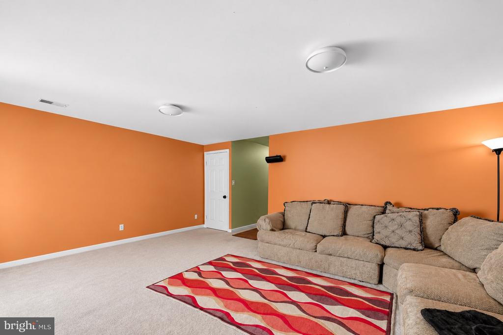 Living room with orange walls, a beige sectional sofa, and a red patterned rug.