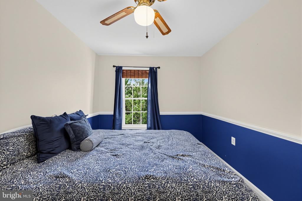 Bedroom with blue-and-white patterned bedding, navy lower walls, and a curtained window.