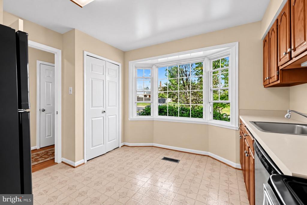 Unfurnished kitchen with a large bay window, beige tile floor, and wood cabinets.