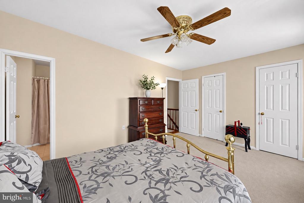 Bedroom with patterned gray bedding, a brass bed frame, and a wooden dresser.