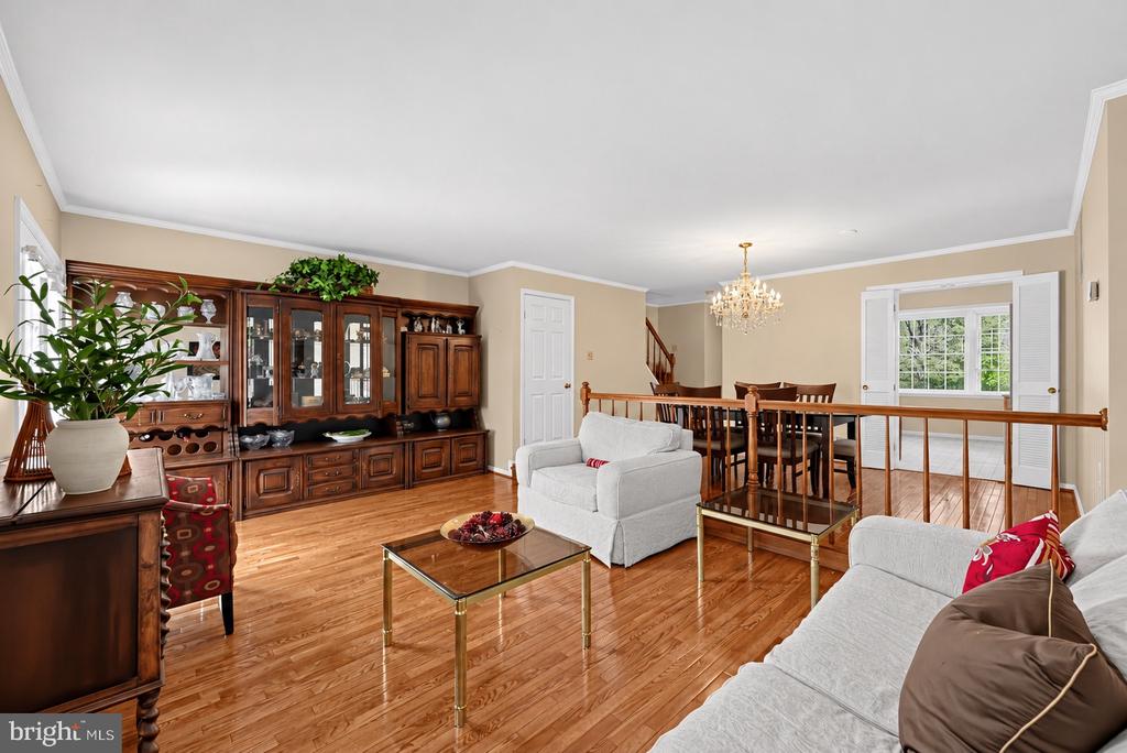 Living room with hardwood floors, light sofas, and a large dark wood china cabinet.