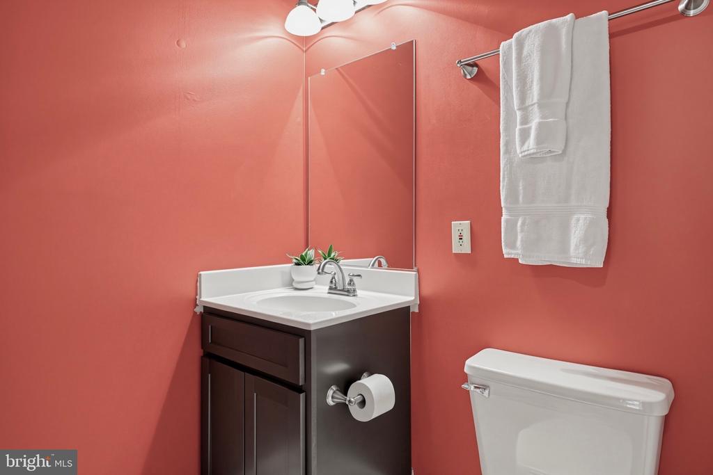 Bathroom vanity with a white sink and mirror against coral-pink walls, with white towels hanging nearby.