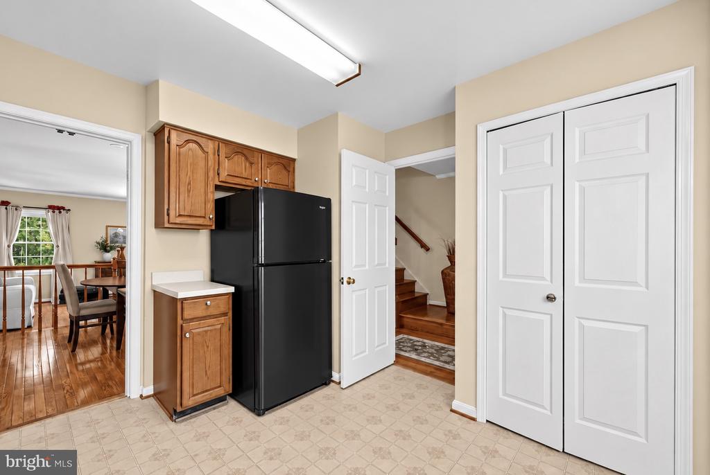 Kitchen with black refrigerator and wood cabinets, opening to a dining area and staircase.
