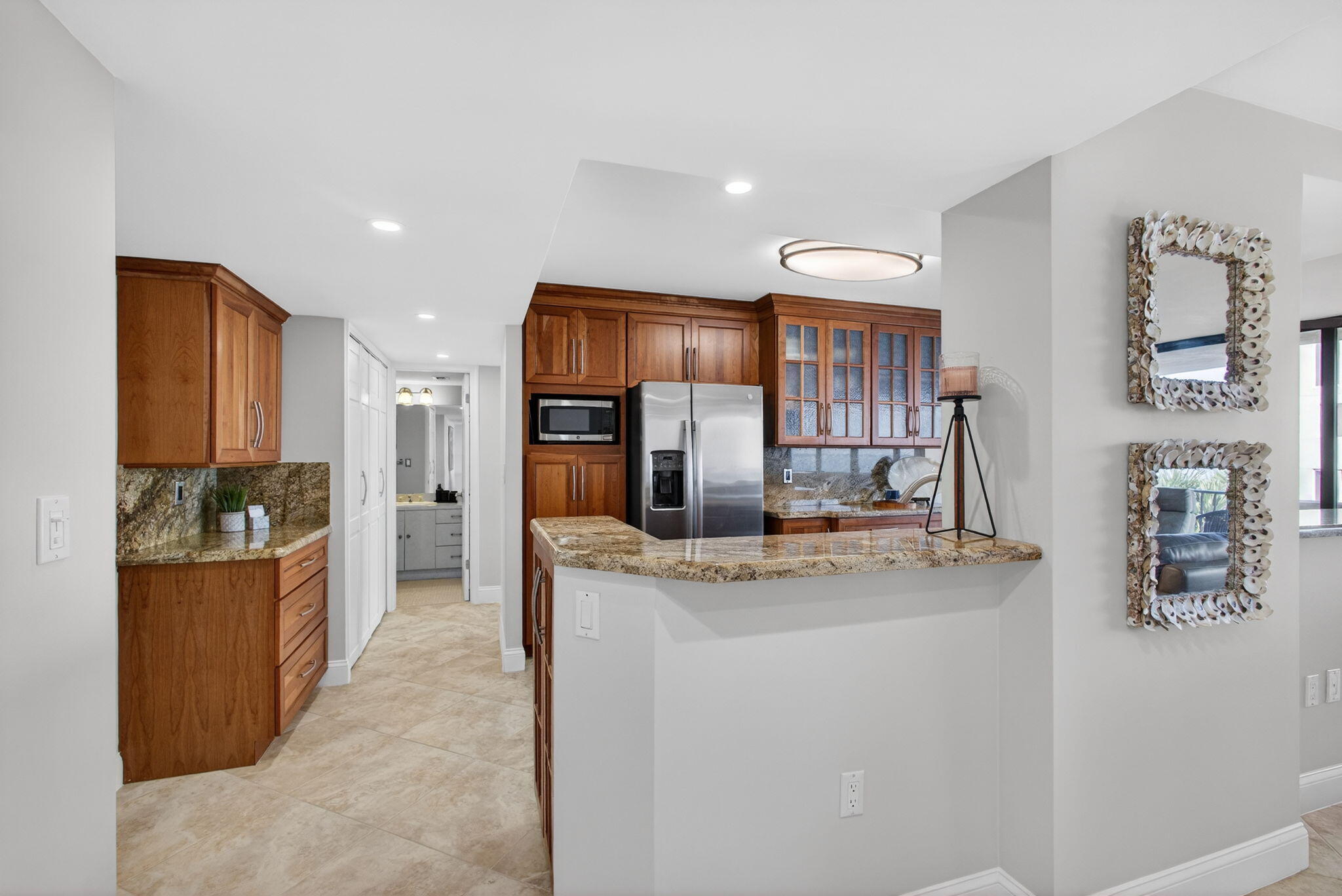 Kitchen with warm wood cabinets, granite counters, stainless steel refrigerator, and a large peninsula.